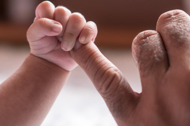 Baby hand holding adult finger